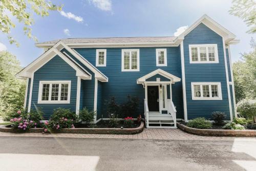 a blue house with a white door at Luxurious Lakeside Chalet with Swim Spa in South Brook