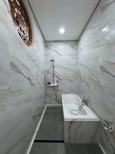 a bathroom with a white tub and marble walls at Casa De Brillo Tegallalang in Tegalalang