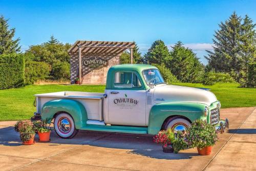 an old green and white truck parked next to potted plants at 2BR Oyhut Bay Condo Fireplace Private Deck in Ocean Shores