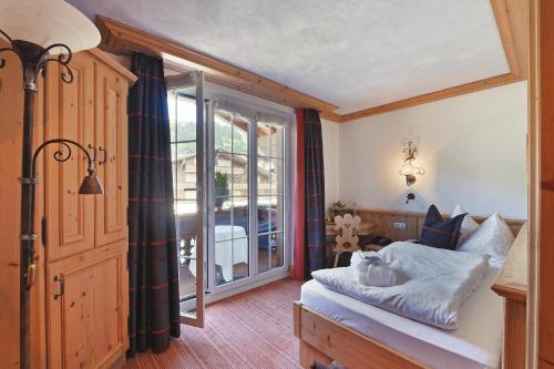 a bedroom with a bed and a large window at ERMITAGE Wellness- & Spa-Hotel in Gstaad