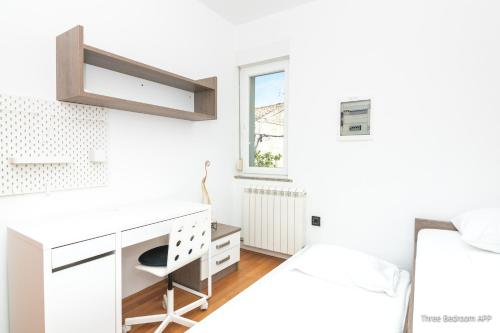 a white bedroom with a desk and a bed at Residence Almarea by Locap Group in Izola