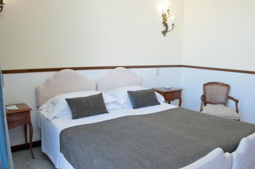 a bedroom with a large white bed with two chairs at Hotel Ristorante Maga Circe in San Felice Circeo