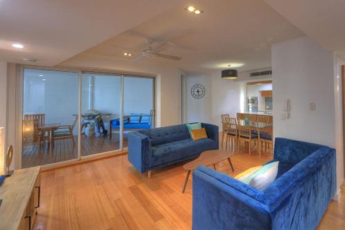 a living room with two blue couches and a table at Maggies Beachfront Apartment 4 in Horseshoe Bay