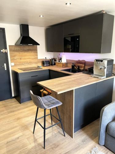 a kitchen with a counter and a chair in it at Appartement cocooning centre ville in Embrun