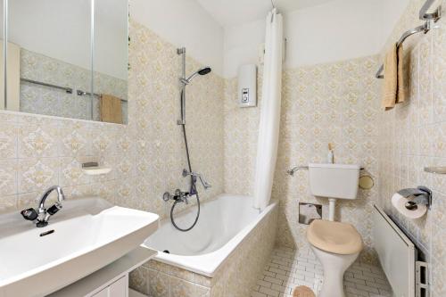 a bathroom with a tub and a sink and a toilet at Grimmingblick Apartment mit Pool in Reith