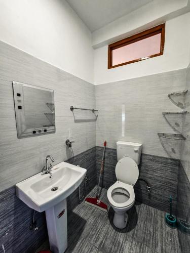 a bathroom with a white toilet and a sink at North Sky Stays Bir in Bīr