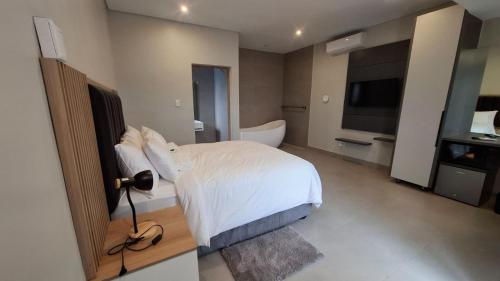 a bedroom with a bed and a bathroom with a television at Lehumo Guesthouse in Mogales