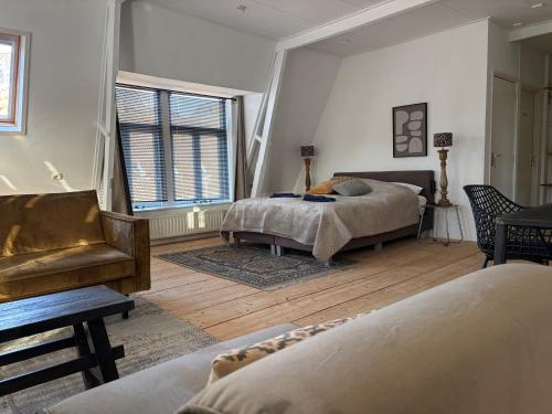 a bedroom with two beds and a couch and a chair at Logement Hoogend in Sneek