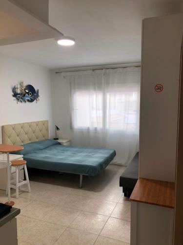 a bedroom with a bed and a table and a window at Roger Apartamentos in Cambrils