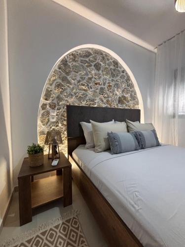 a bedroom with a large bed with a stone wall at Bougainvillea in Asklipiḯon