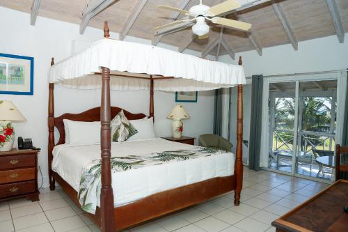 a bedroom with a canopy bed with a ceiling fan at Oualie Beach Resort in Nevis