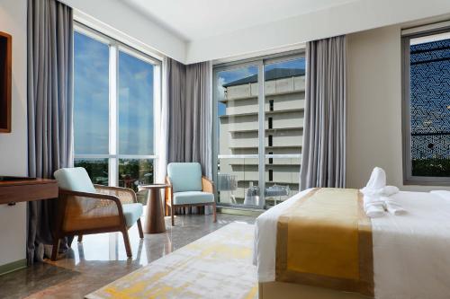a hotel room with a bed and chairs and windows at Abantu Hotel in Dar es Salaam
