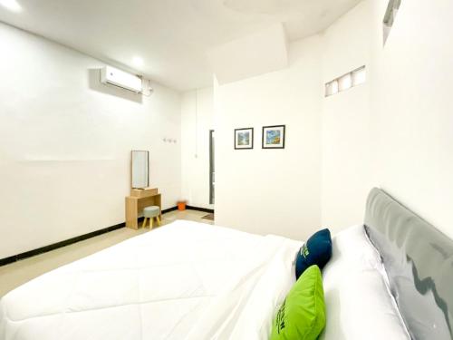 a bedroom with a large white bed with green pillows at Urbanview Bangsal Mojokerto in Ngranggon