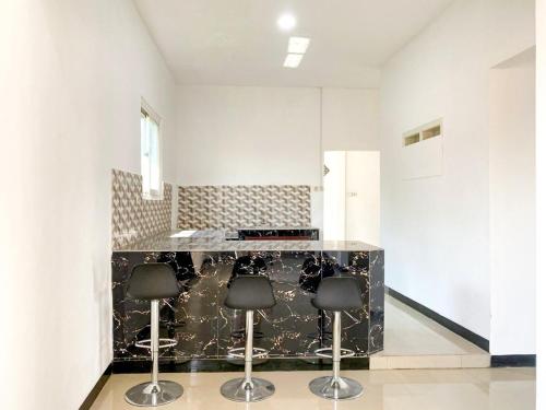 a kitchen with a black counter and three stools at Urbanview Bangsal Mojokerto in Ngranggon