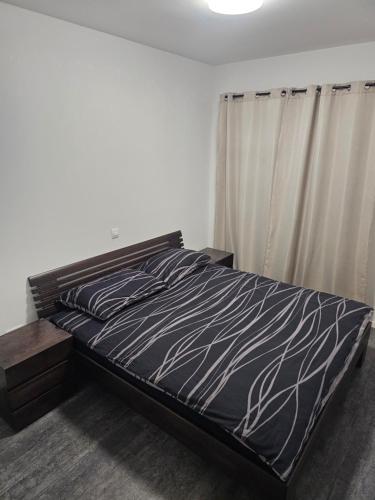 a bedroom with a bed with a black and white comforter at Apartman Rena in Ivanec