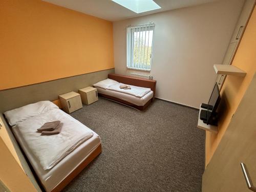 a small room with two beds and a television at Penzion U Bártů, Dešov in Desov