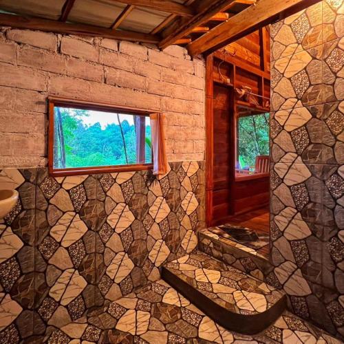 a room with a window and a stone wall at Fuma Bungalow Tetebatu in Tetebatu