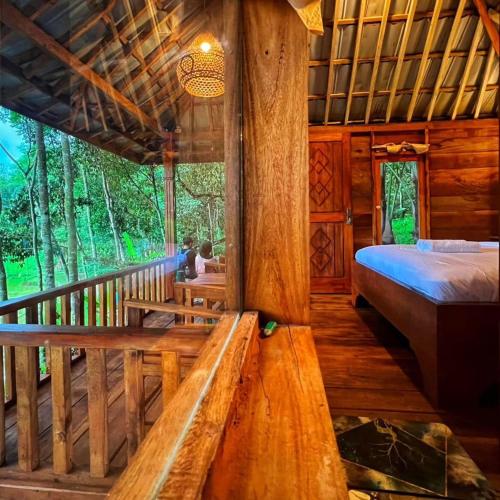 a bedroom in a tree house with a bed and benches at Fuma Bungalow Tetebatu in Tetebatu