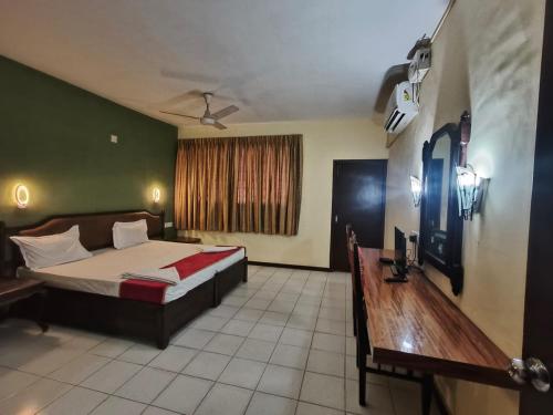 a bedroom with a bed and a desk in it at Bluemoon Hotel in Cochin