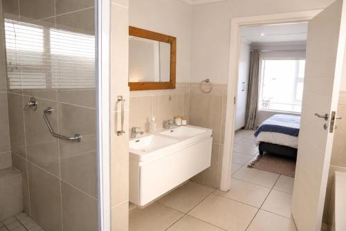 a bathroom with a sink and a shower and a mirror at Die Koraalbos in Stilbaai-Oos