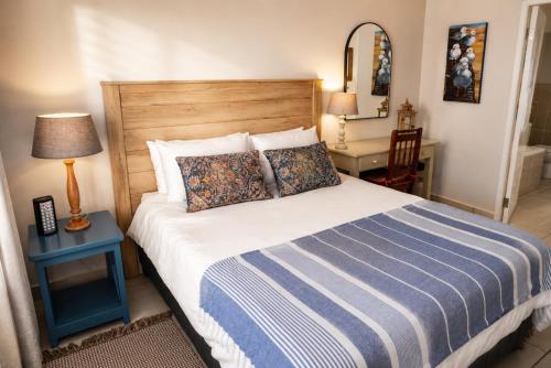 a bedroom with a bed with a blue and white comforter at Die Koraalbos in Stilbaai-Oos