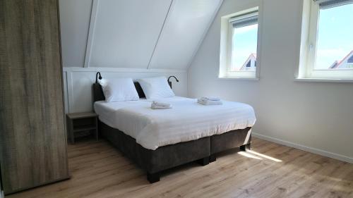 a bedroom with a bed with white sheets and two windows at Villapark Wulpdal | Villa De Wulp in Scherpenisse