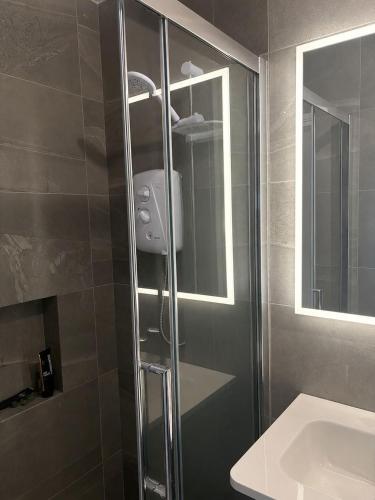a bathroom with a shower with a sink and a mirror at The Cloverhill House in Mullaghbane