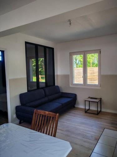 a living room with a blue couch and a table at Studio indépendant tout équipé proche circuit des 24 Heures in Teloché