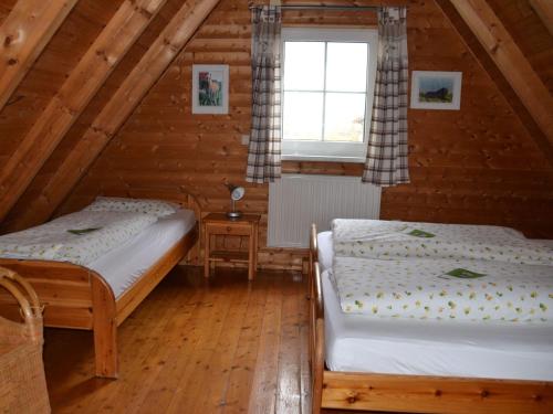two beds in a attic room with a window at Fränkischer Ferienhof Joas in Gerolfingen