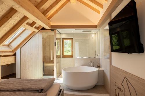a large bathroom with a tub and a tv in it at Casera Malvan, private wellness chalet in Belluno