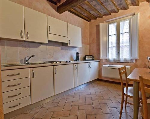 kuchnia z białymi szafkami, stołem i oknem w obiekcie Casa Vacanze Il Campo w Sienie