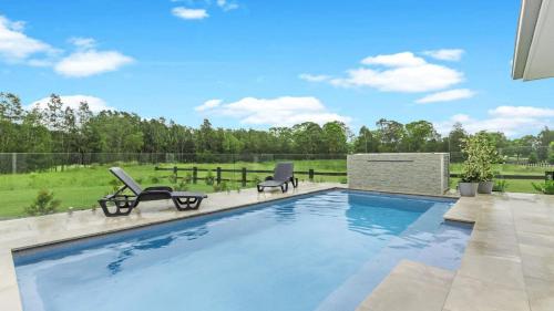 a swimming pool with two lounge chairs next to at Kokoon in Pokolbin
