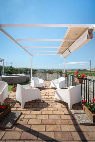 a patio with white chairs and an umbrella at Oasi Orange Villa with Jacuzzi in Paterno