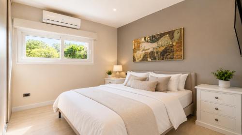 a bedroom with a white bed and a window at Luxury Home & Pool by Symphonya Luxury Holiday Rentals in Lequile