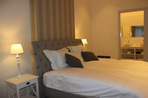 a bedroom with a large white bed and a lamp at The Hamptons Boutique Hotel in Ghent