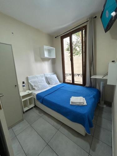 a bedroom with a bed with blue sheets and a window at myappart - La Garenne in La Garenne-Colombes