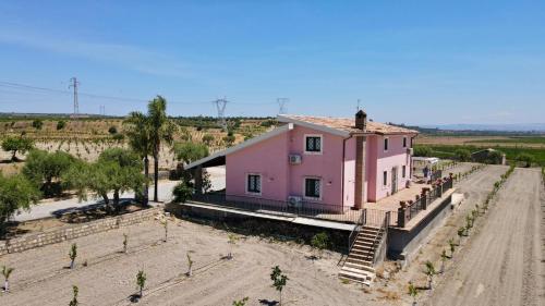 a pink house in the middle of a dirt road at Oasi Orange Villa with Jacuzzi in Paterno