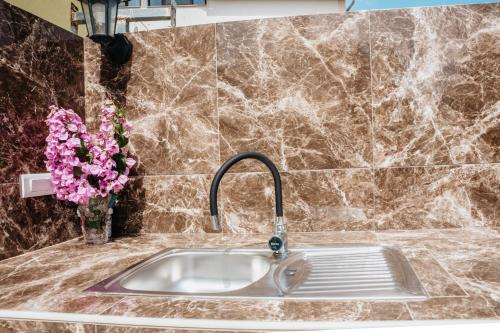 a kitchen sink with a vase of pink flowers at Apartmani Saric A&K in Vir