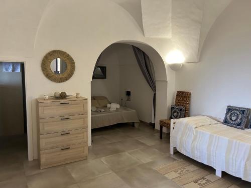 a bedroom with a bed and a dresser and a mirror at Dammuso Rekhale con vista mare in Scauri