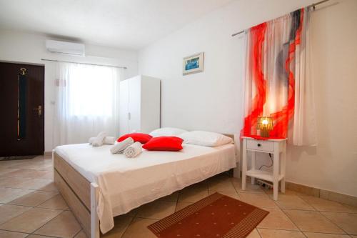 a bedroom with a bed with red pillows and a window at Old Town Accommodation in Bol
