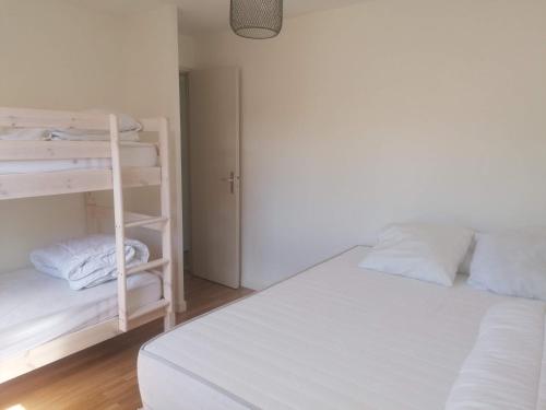a bedroom with a white bed and bunk beds at Le petit paradis in Soustons