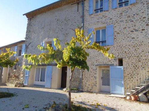a building with blue doors and a tree in front of it at Campagne Vallauris chambres in Sisteron