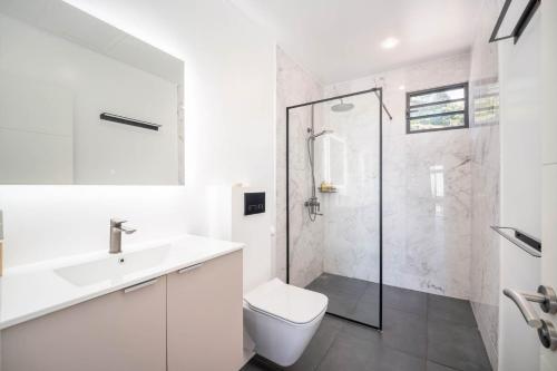 a white bathroom with a shower and a toilet at Peperu Lodge - bungalow piscine privée in Punaauia