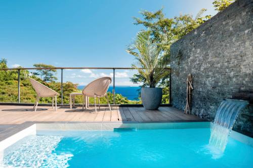 a pool with two chairs and a table on a deck at Peperu Lodge - bungalow piscine privée in Punaauia