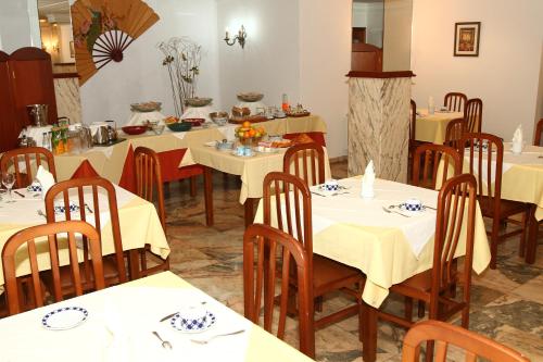 um restaurante com mesas brancas e cadeiras de madeira em Hotel Jr em Villalonga