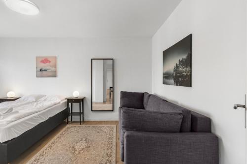 a bedroom with a couch and a bed and a mirror at AirHosted - Lucerne City Centre in Lucerne
