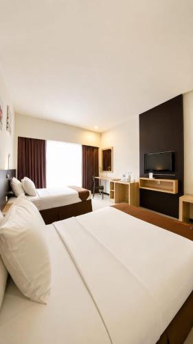 a hotel room with two beds and a flat screen tv at Batusuki Resort & Hotel in Batu