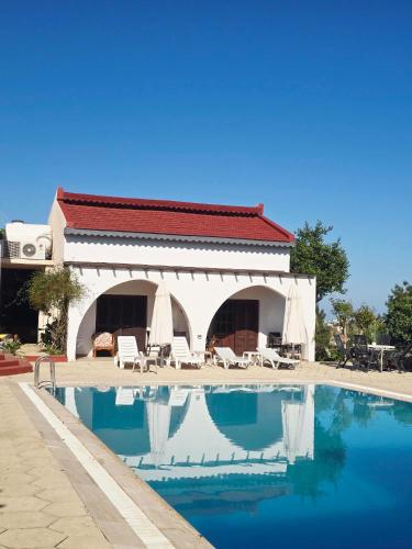 a swimming pool in front of a house with a building at Five Fingers Holiday Bungalows in Kyrenia