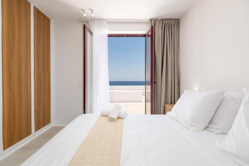 a bedroom with a large white bed with a view of the ocean at Proper Stone Villa - Antiparos in Agios Georgios