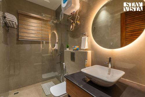 a bathroom with a sink and a toilet and a mirror at StayVista at The Cloudberry Crest with BBQ & Bonfire in Rāmgarh